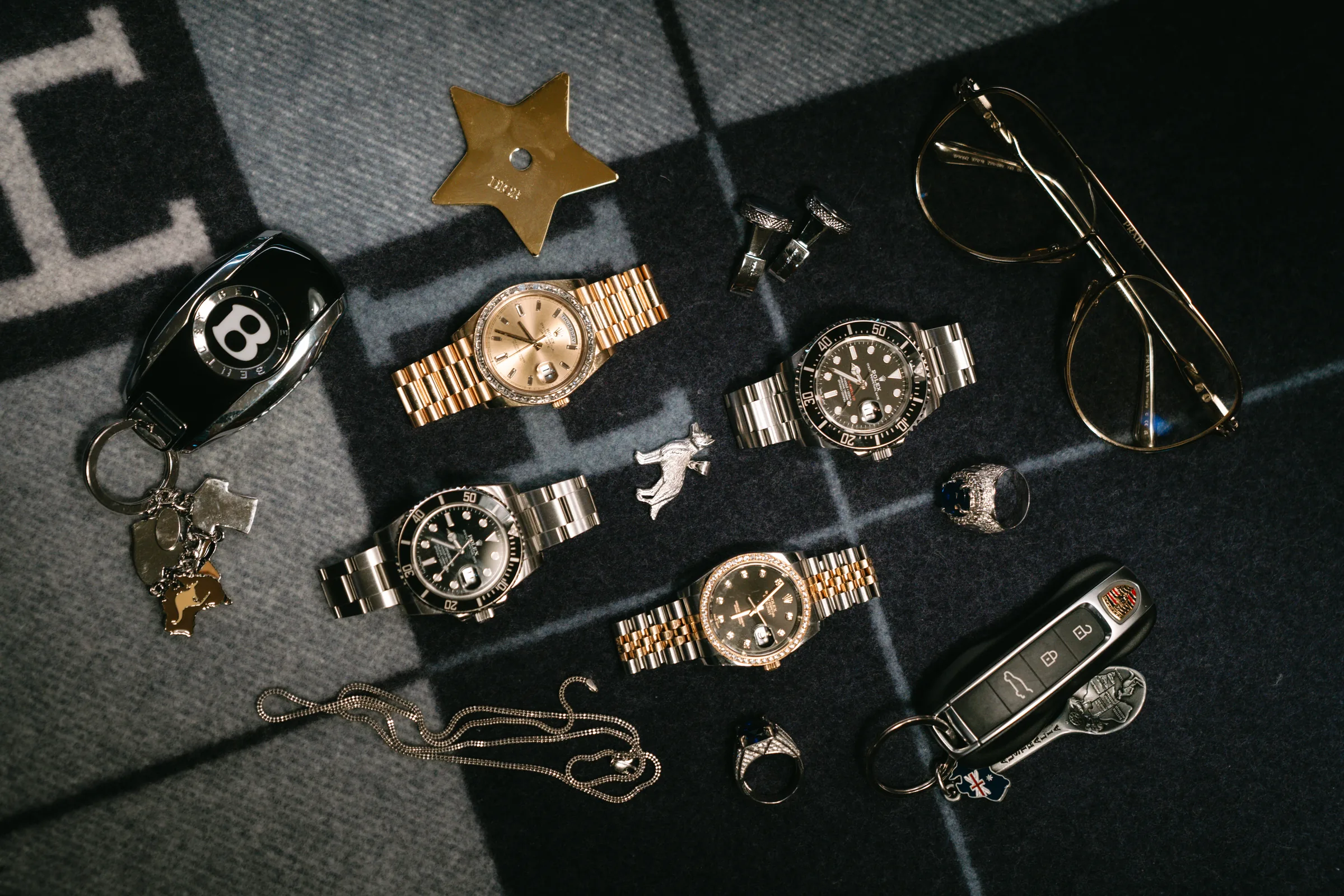 A flat-lay of Rolex watches, rings and car keys on a wool blanket